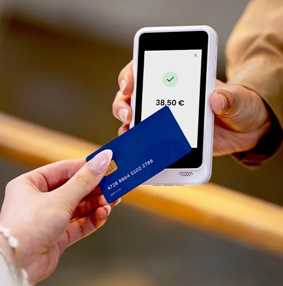 Person holds a bank card to a payment terminal for a contactless payment of 38.50 euros.