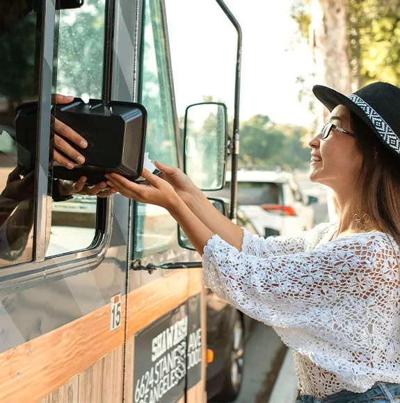 Woman receives a black takeaway container from a food truck.