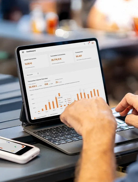 A person is using a tablet with a dashboard to analyse sales and transaction data in a beer garden.