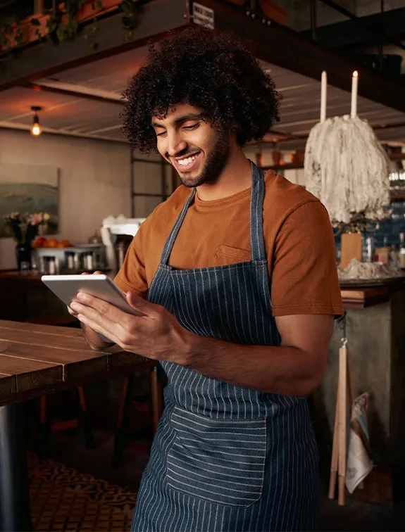Waiter operates a tablet and smiles while managing orders.