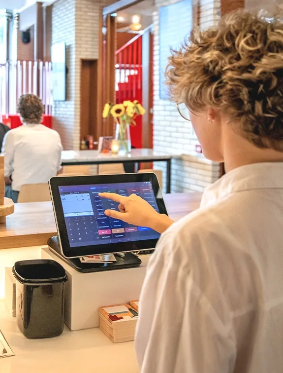 Waitress taps on the screen of a POS system to take an order.
