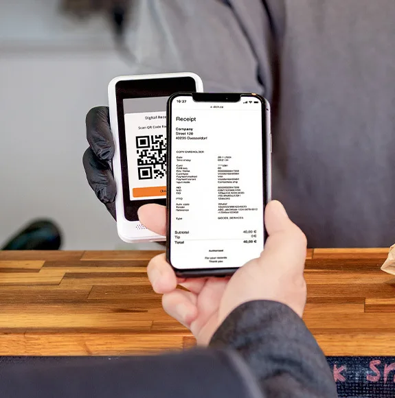 Smartphone displaying digital receipt with QR code next to a payment terminal.