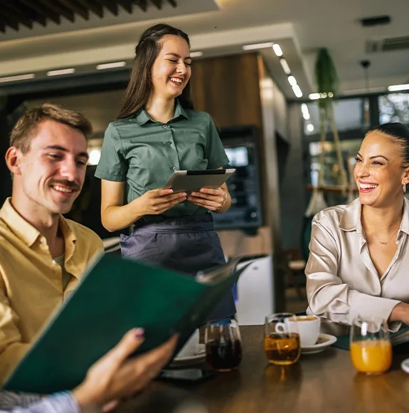 Un serveur prend la commande d'un groupe joyeux de clients dans le restaurant à l'aide d'une tablette.