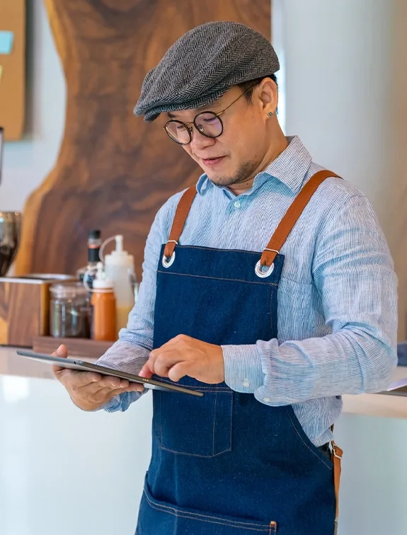 Café employee works with a tablet to manage digital orders and menus.
