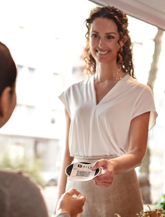 Una cameriera consegna a un cliente una ricevuta con un codice QR per avviare un pagamento contactless.