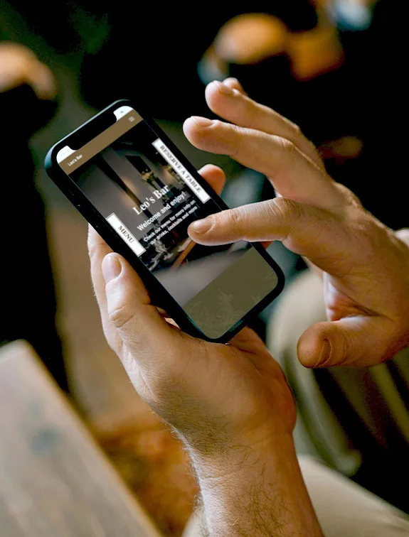 Una persona tiene uno smartphone con il sito web del bar aperto e naviga nel menu.