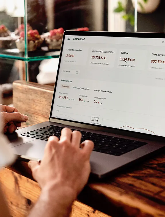 Un laptop afișează un tablou de bord cu statistici de vânzări și date despre tranzacții în euro.