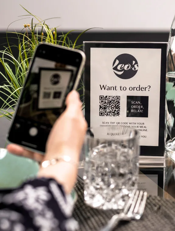 El cliente escanea un código QR en un display de mesa con su smartphone para hacer un pedido.
